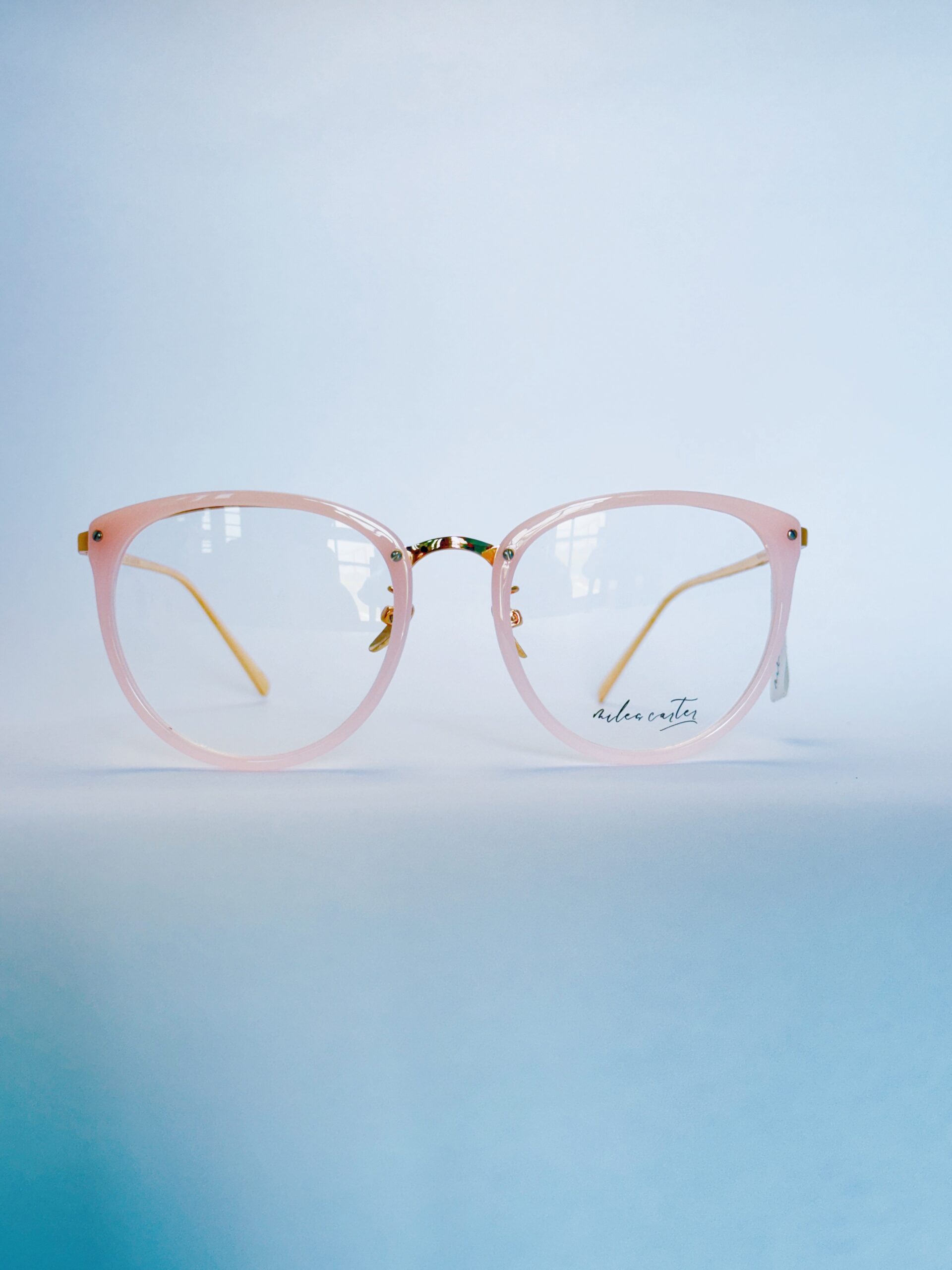 Stylish light pink round eyeglasses with subtle gold metallic detailing and clear lenses.