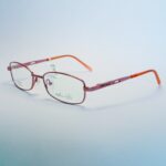 Stylish pink metal rectangular eyeglasses with orange temple tips, ideal for fashion and vision enhancement." . Available at website - www.spexovision.com