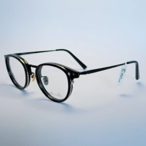 Black round eyeglasses with transparent lenses and metal bridge, displayed on a soft gradient background. Available at www.spexovision.com