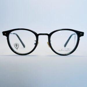 Black round eyeglasses with transparent lenses and metal bridge, displayed on a soft gradient background. Available at www.spexovision.com